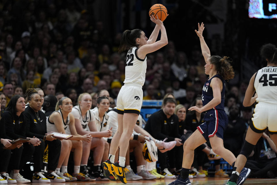 Iowa guard Caitlin Clark (22) shoots a three-point basket over UConn guard Ashlynn Shade, right, during the second half of a Final Four college basketball game in the women's NCAA Tournament, Friday, April 5, 2024, in Cleveland. (AP Photo/Carolyn Kaster)