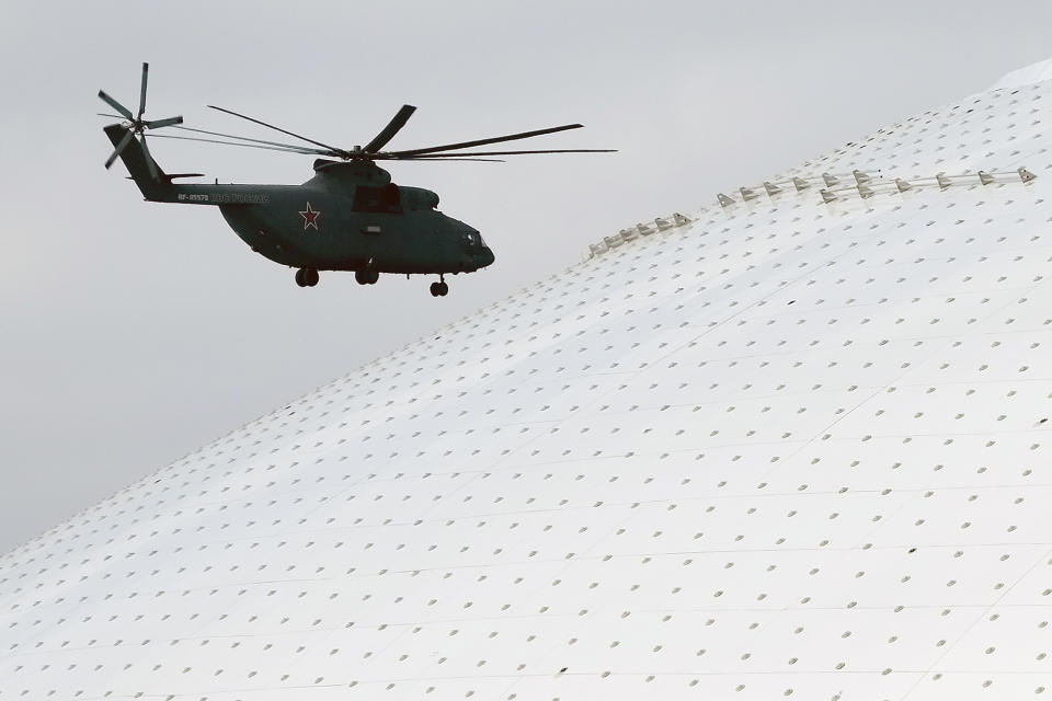 A Russian military helicopter flies past the Bolshoy Ice Dome, site of the ice hockey competitions, ahead of the 2014 Winter Olympics, Wednesday, Feb. 5, 2014, in Sochi, Russia. (AP Photo/J. David Ake)