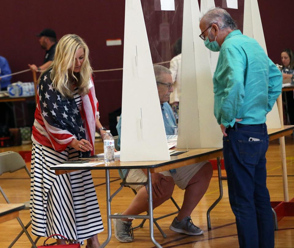 A ballot clerk wears a patriotic scarf as she checks people in to get their ballots in Portsmouth's Ward 2, the city's middle school, during the New Hampshire primary Tuesday, Sept. 13, 2022.