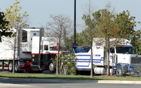 Police prepare to tow and 18-wheeler trailer parked behind a Walmart store after eight people believed to be illegal immigrants being smuggled into the United States were found dead inside it in San Antonio, Texas, U.S. July 23, 2017. REUTERS/Ray Whitehouse