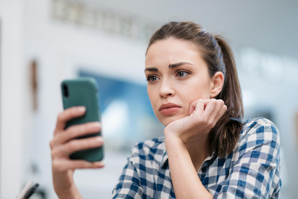 A sad woman looking at her phone