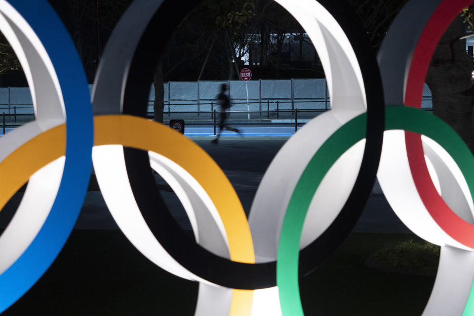 FILE - In this March 30, 2020, file photo, a man jogs past the Olympic rings in Tokyo. Former Olympic minister Toshiaki Endo said at a meeting of the ruling Liberal Democratic Party on Friday, June 5, 2020, that a decision of whether to hold the Games should be made around March, which is a crucial time to finalize participating athletes, NHK said. (AP Photo/Jae C. Hong, File)