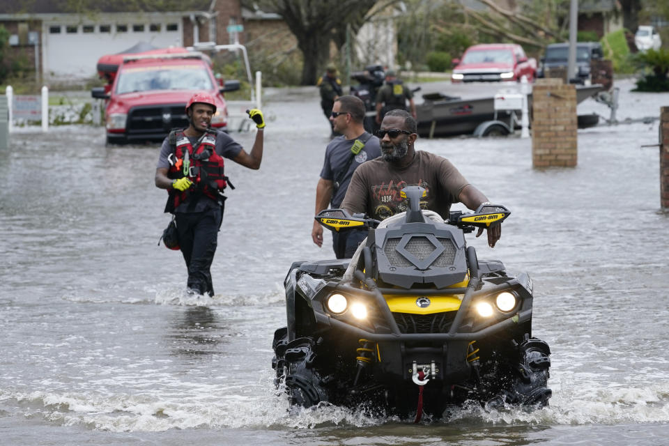 A resident of the Spring Meadow subdivision drives a four wheeler out of flood waters followed by rescue personnel after Hurricane Ida moved through Monday, Aug. 30, 2021, in LaPlace, La. (AP Photo/Steve Helber)