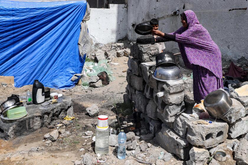 A woman washes pots outside a tent pitched by a destroyed building in Rafah in the southern Gaza Strip on April 5, 2024 amid the ongoing conflict in the Palestinian territory between Israel and the militant group Hamas. (Photo by MOHAMMED ABED / AFP) (Photo by MOHAMMED ABED/AFP via Getty Images)