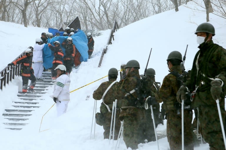 Firefighters carry a survivor from the site of an avalanche in Tochigi prefecture, Japan