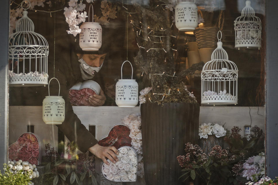 A staff member of a flower shop sets up merchandise in the window in Budapest, Hungary, Wednesday April 7, 2021. Hungary's government lifted several lockdown restrictions on Wednesday, even as some doctors and medical experts urged caution after a record-breaking day of COVID-19 deaths, a move that came as Hungary reached 2.5 million first-dose vaccinations, a benchmark the government set for when a gradual reopening could move forward. (AP Photo/Laszlo Balogh)