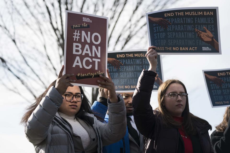 People hold signs in support of ending a ban on travel to the United States