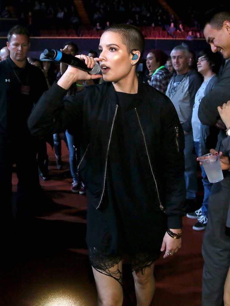 Halsey with a microphone wearing a dark outfit with lace detail