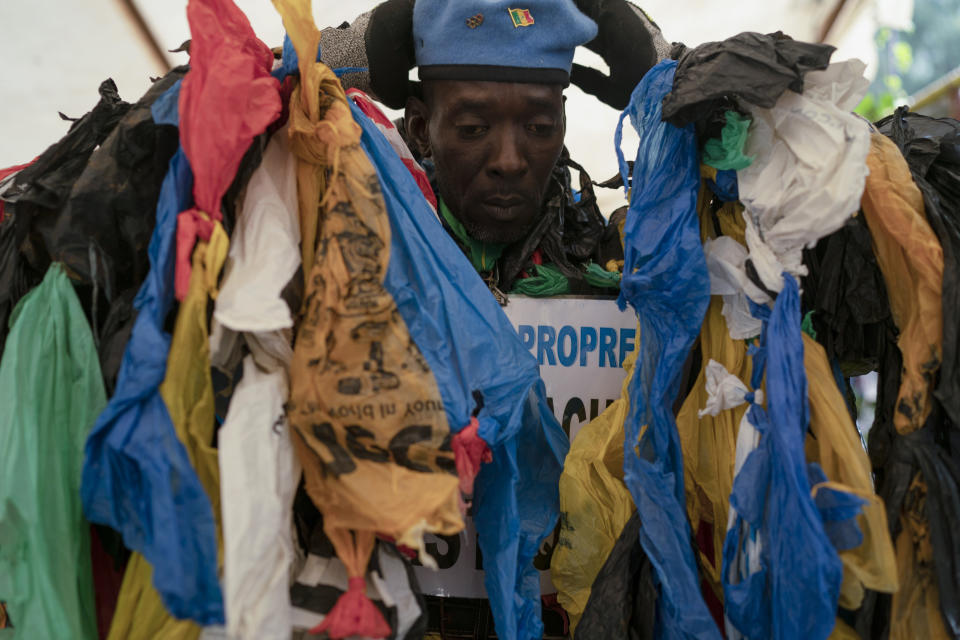 The environmental activist Modou Fall, who many simply call "Plastic Man", wears his uniform before an event about environmental health and pollution management in Dakar, Senegal, Tuesday, Nov. 8, 2022. As he walks, plastics dangle from his arms and legs, rustling in the wind while strands drag on the ground. On his chest, poking out from the plastics, is a sign in French that says, "No to plastic bags." (AP Photo/Leo Correa)
