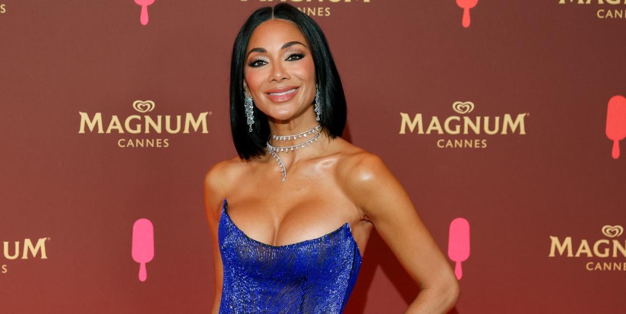 nicole scherzinger wearing a dark blue strapless gown with diamond earrings and a diamond necklace, smiling for the camera at a red carpet event