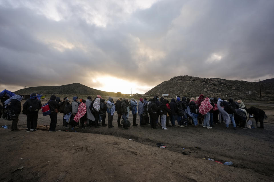 FILE - Asylum-seeking migrants line up in a makeshift, mountainous campsite to be processed after crossing the border with Mexico, Friday, Feb. 2, 2024, near Jacumba Hot Springs, Calif. The arrest of a Venezuelan man who entered the U.S. illegally for the murder of a 22-year-old nursing student in Georgia has triggered fiery reactions from Donald Trump and his allies. Trump blamed President Joe Biden and his immigration policies for the fatal beating of 22-year-old Laken Riley while on her morning run. (AP Photo/Gregory Bull, File)