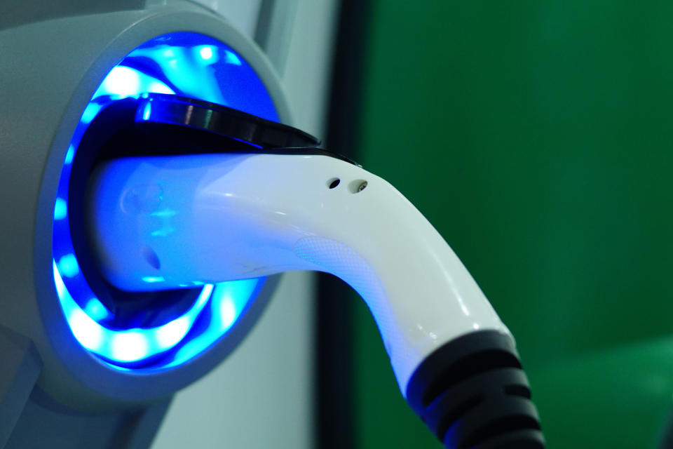 A plugged in electric vehicle charger with glowing blue lights