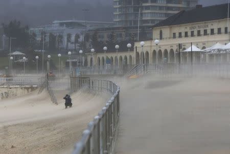 A man takes a picture of Bondi Beach's sand as heavy winds blow it inland, April 21, 2015. REUTERS/Jason Reed