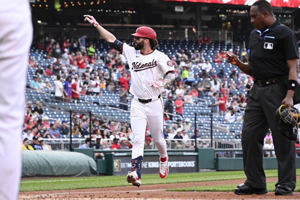 Washington Nationals' Jesse Winker, center, celebrates after his home run during the fourth inning of a baseball game against the Minnesota Twins, Monday, May 20, 2024, in Washington. Home plate umpire Ramon DeJesus, right, looks on. (AP Photo/Nick Wass)