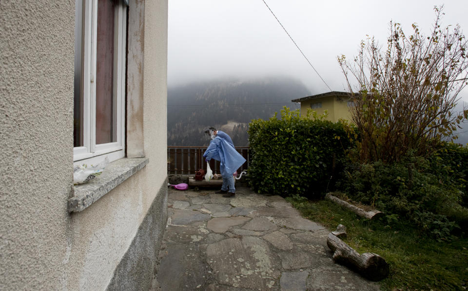 Doctor Mauro Morganti removes his protective gear after doing a house call on a COVID-19 patient, in Campo Tartano, near Sondrio, Italy, Tuesday, Dec. 1, 2020. (AP Photo/Antonio Calanni)