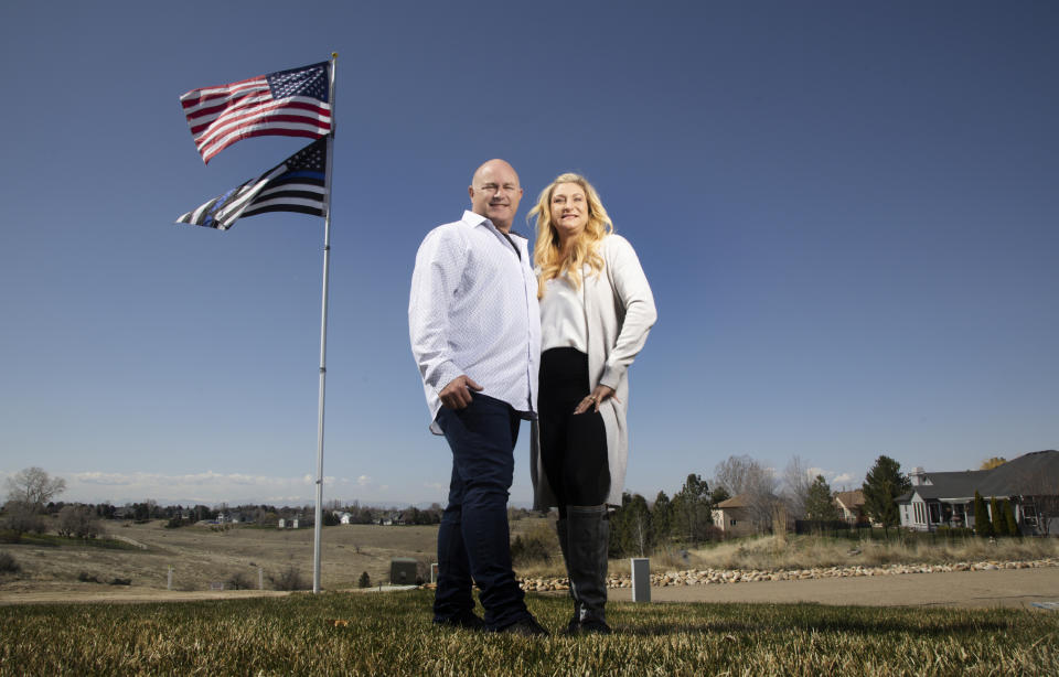 Jennifer y Tim Kohl posa para una fotografía en su jardín delantero con la bandera estadounidense y una bandera azul el 14 de abril de 2023, en Star, Idaho. La pareja se mudó recientemente a Idaho desde el área de Los Ángeles. (AP Foto/Kyle Green)