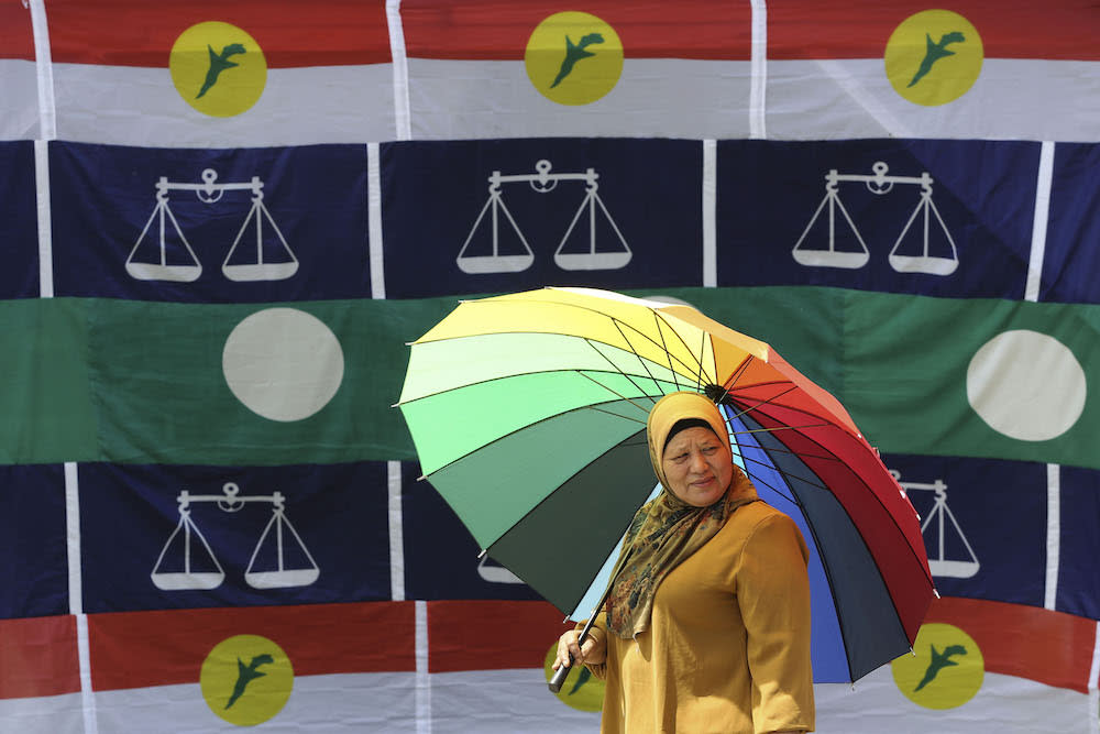 A woman walks past Umno, Barisan Nasional and PAS flags in Pekan Kuala Sawah, Rantau April 10, 2019. — Picture by Yusof Mat Isa