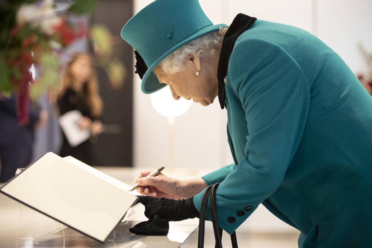 The Queen signs a book as she formally opens the new headquarters of Schroders back 2018 in London, England. (WPA Pool/Getty Images)