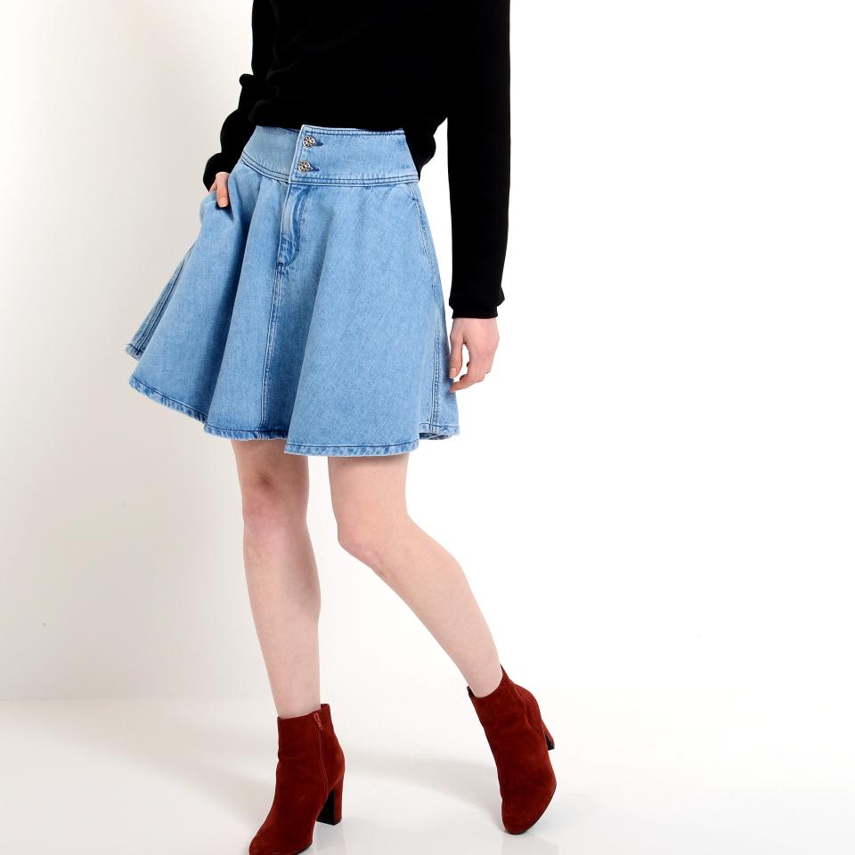 Person modeling an outfit composed of a black top, blue denim skirt, and red ankle boots