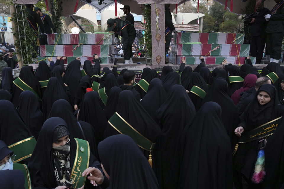 Mourners attend a funeral procession for a group of unknown Iranian soldiers who were killed during the 1980-88 Iran-Iraq war, whose remains were recently recovered in the battlefields, as their coffins are carried on a truck, in Tehran, Iran, Tuesday, Dec. 27, 2022. (AP Photo/Vahid Salemi)