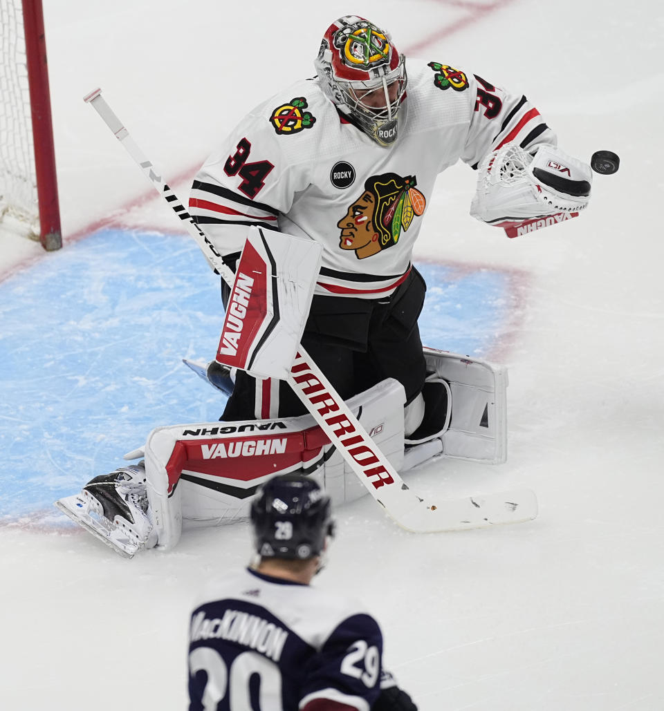 Chicago Blackhawks goaltender Petr Mrazek, top, makes a glove-save of a shot by Colorado Avalanche center Nathan MacKinnon, bottom, in the second period of an NHL hockey game Monday, March 4, 2024, in Denver. (AP Photo/David Zalubowski)