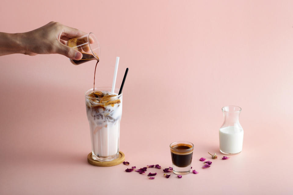 Close-Up Of Hand Pouring coffee Syrup In Glass in a pink background. For people who experience intolerance to coffee, it could actually be what they're putting in the coffee. (Getty)