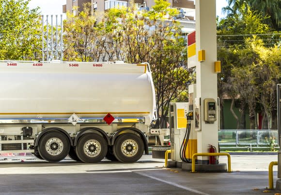 Natural gas tanker parked next to a fuel pump.