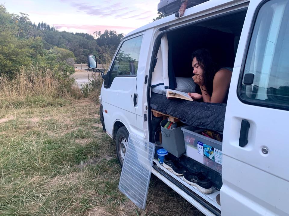 the writer's boyfriend reading while looking out of the open side of a van