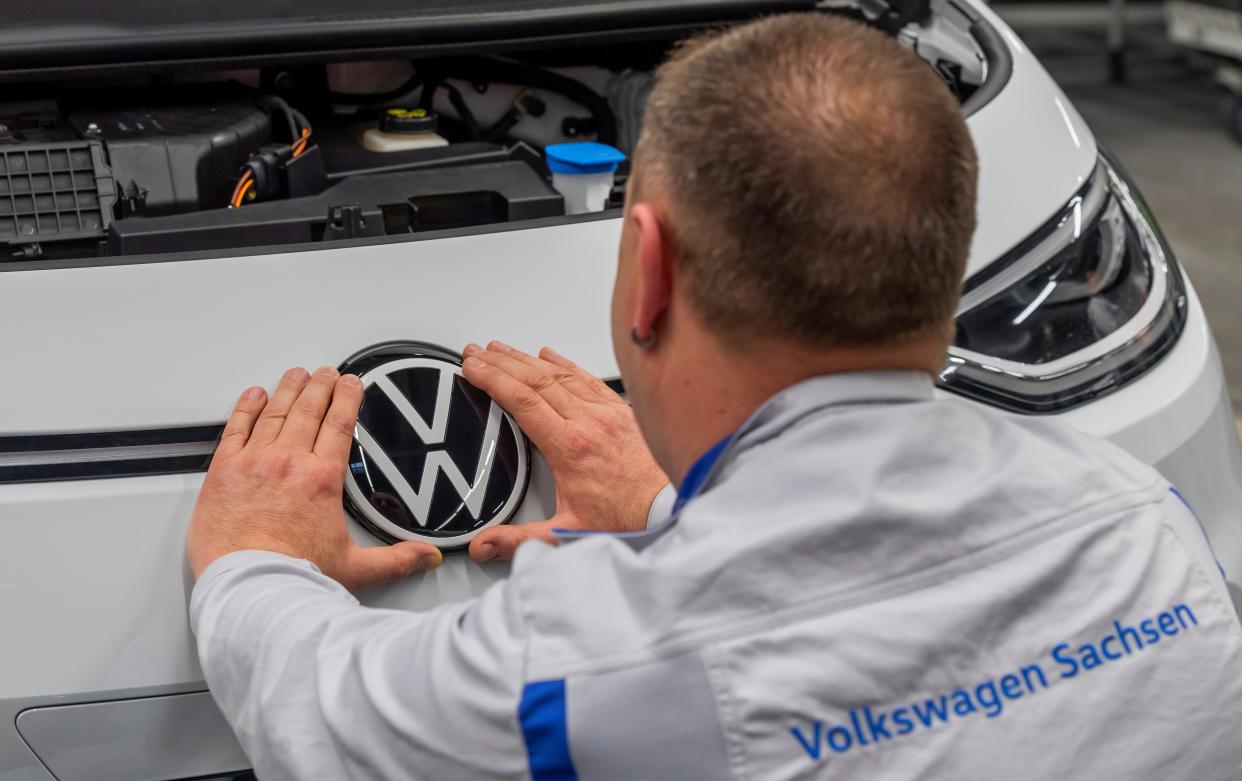FILE PHOTO: An employee fixes a VW sign at a production line of the electric Volkswagen model ID.3 in Zwickau, Germany, February 25, 2020. REUTERS/Matthias Rietschel