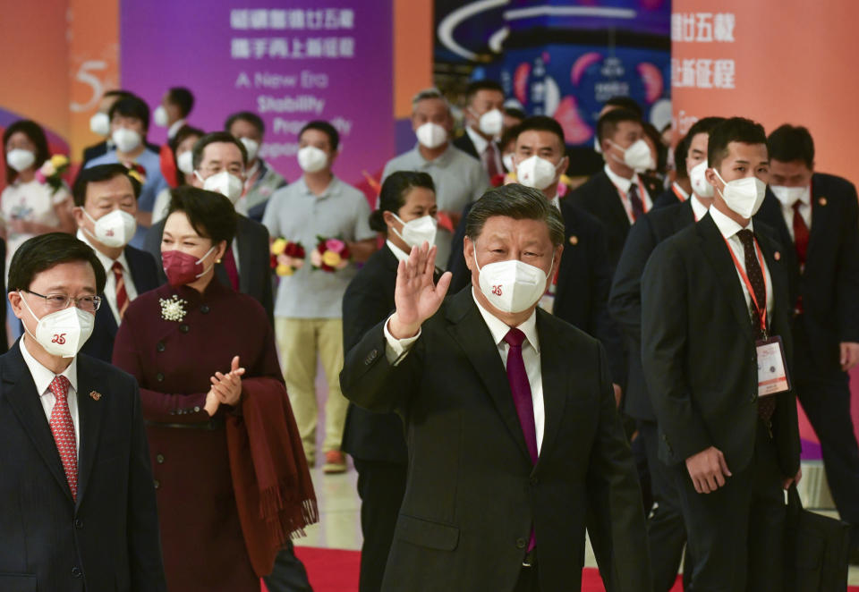 In this photo provided by Hong Kong Government Information Services, Chinese president Xi Jinping, center, and his wife Peng Liyuan, second from left, accompanied with Chief Executive John Lee, left, wave as they depart at the West Kowloon Station of the Guangzhou-Shenzhen-Hong Kong Express Rail Link in Hong Kong, Friday, July 1, 2022. (Hong Kong Government Information Services via AP)