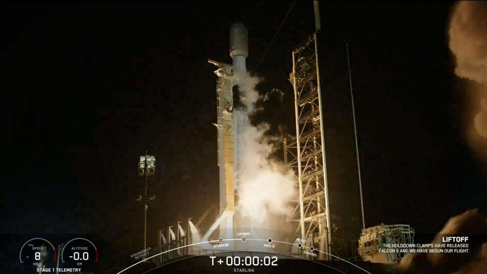  A black-and-white spacex falcon 9 rocket launches into a night sky. 