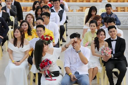 Newlywed couples react during a mass wedding in Kuala Lumpur