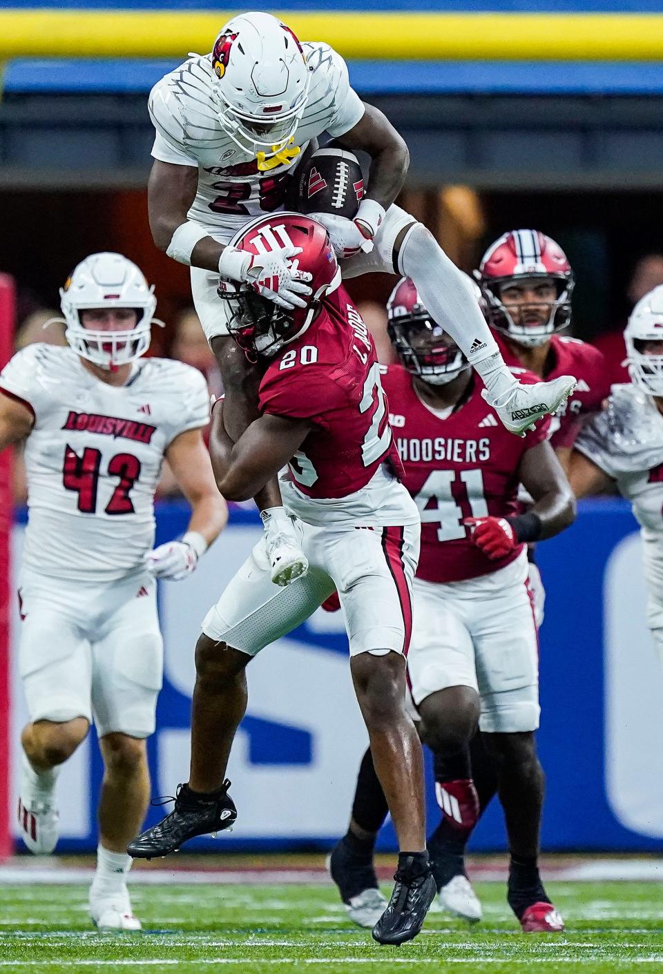 Louisville Cardinals running back Jawhar Jordan (25) leaps over Indiana Hoosiers defensive back Louis Moore (20) on Saturday, Sept. 16, 2023, during the game at Lucas Oil Stadium in Indianapolis. The Louisville Cardinals defeated the Indiana Hoosiers, 21-14.