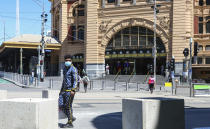 A man wearing a mask walks past Flinders Street Station in Melbourne, Australia, Wednesday, Oct. 28, 2020. In Melbourne, Australia's former coronavirus hot spot, restaurants, cafes and bars were allowed to open and outdoor contact sports can resume Wednesday, emerging from a lockdown due to the coronavirus outbreak. (AP Photo/Asanka Brendon Ratnayake)