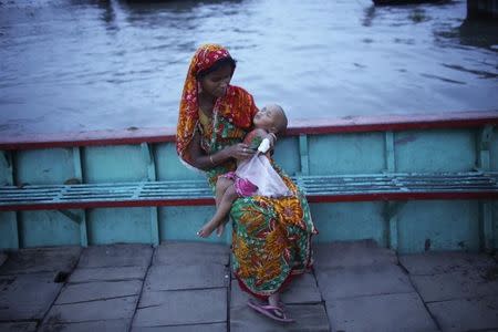 A woman eats food with her child as she breaks her fast by the river Buriganga in Dhaka in this file photo taken on July 2, 2014. REUTERS/Andrew Biraj