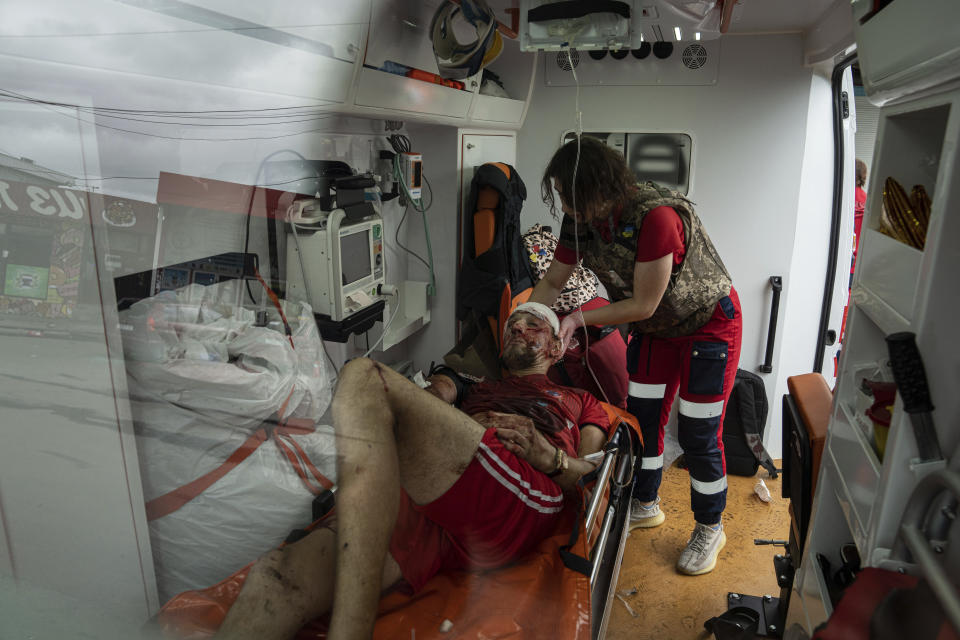 A paramedic assists an injured man in an ambulance after a Russian attack at Barabashovo market in Kharkiv, Ukraine, Thursday, July 21, 2022. (AP Photo/Evgeniy Maloletka)