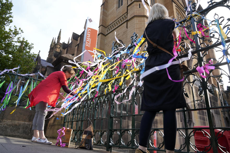 Protesters tie ribbons as a symbol of support to sex abuse victims to a fence at St. Mary's Cathedral where Cardinal George Pell's coffin will be brought to lay in state in Sydney, Wednesday, Feb. 1, 2023. Pell, who was once considered the third-highest ranking cleric in the Vatican and spent more than a year in prison before his child abuse convictions were squashed in 2020, died in Rome last month at age 81. (AP Photo/Rick Rycroft)