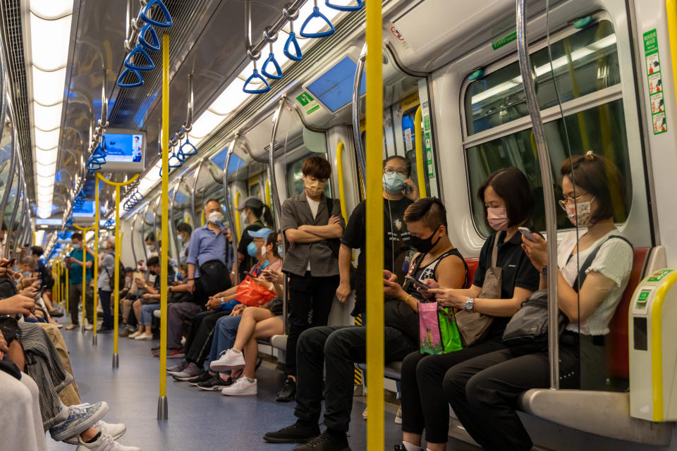 Hong Kong - April 29, 2022 : Passengers wearing face masks at MTR Tuen Ma Line train in Hong Kong.