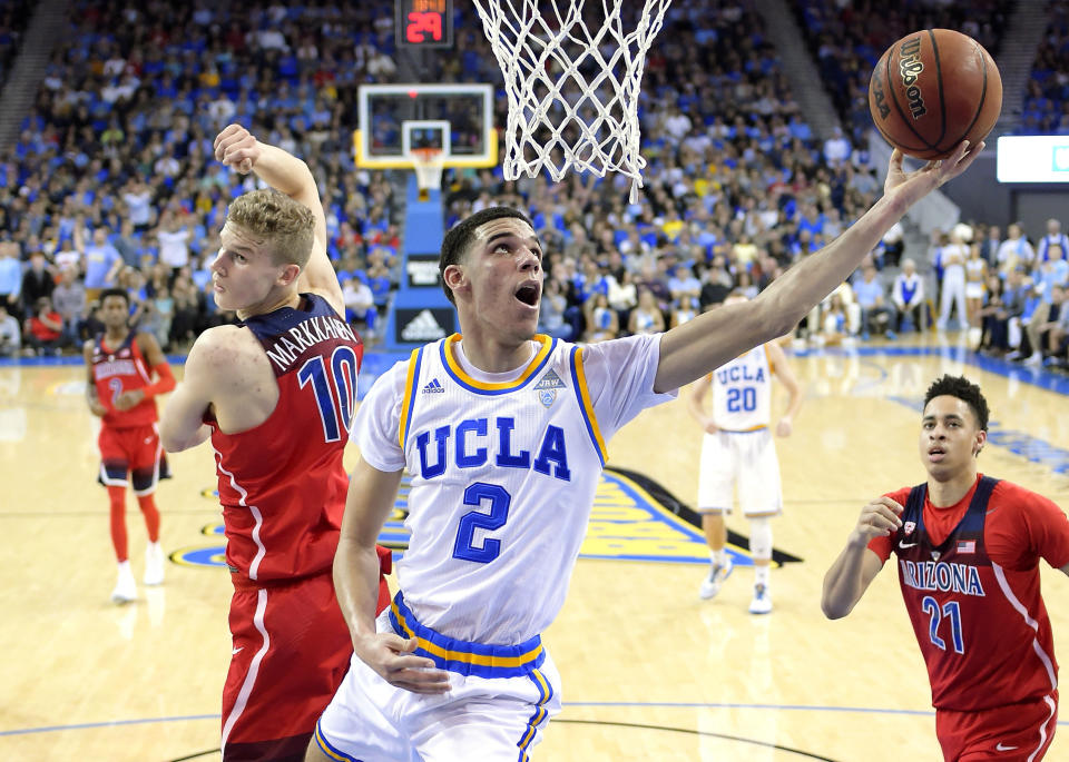 UCLA guard Lonzo Ball, center, shoots as Arizona forward Lauri Markkanen, left, and center Chance Comanche defend during the first half of an NCAA college basketball game, Saturday, Jan. 21, 2017, in Los Angeles. (AP Photo/Mark J. Terrill)