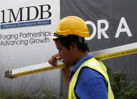 A construction worker walks past a 1Malaysia Development Berhad (1MDB) billboard at the Tun Razak Exchange development in Kuala Lumpur, Malaysia February 3, 2016. REUTERS/Olivia Harris/File Photo