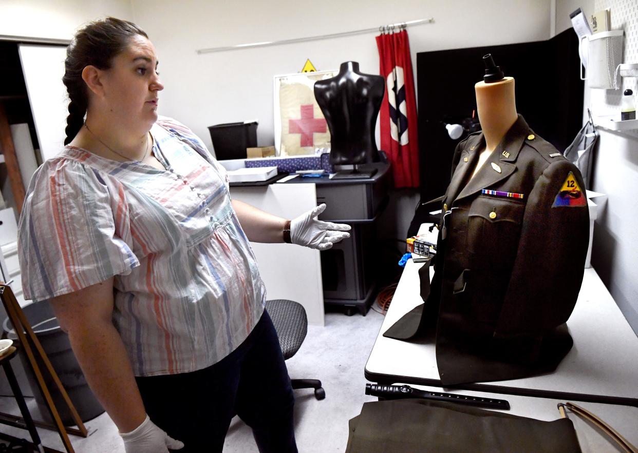 Mikayla Spivey, the executive director of the 12th Armored Division Memorial Museum, on Thursday stands beside a US Army World War II officers' service jacket which was damaged recently by mold. The museum’s three air conditioning units began failing in the recent record heat, allowing for mold to grow on uniforms as heat and humidity combined to make conditions right.