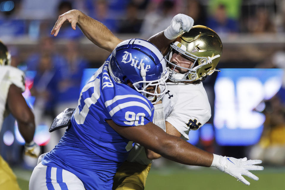 Notre Dame quarterback Sam Hartman, right, is hit as he throws by Duke's DeWayne Carter (90) during the first half of an NCAA college football game in Durham, N.C., Saturday, Sept. 30, 2023. (AP Photo/Ben McKeown)