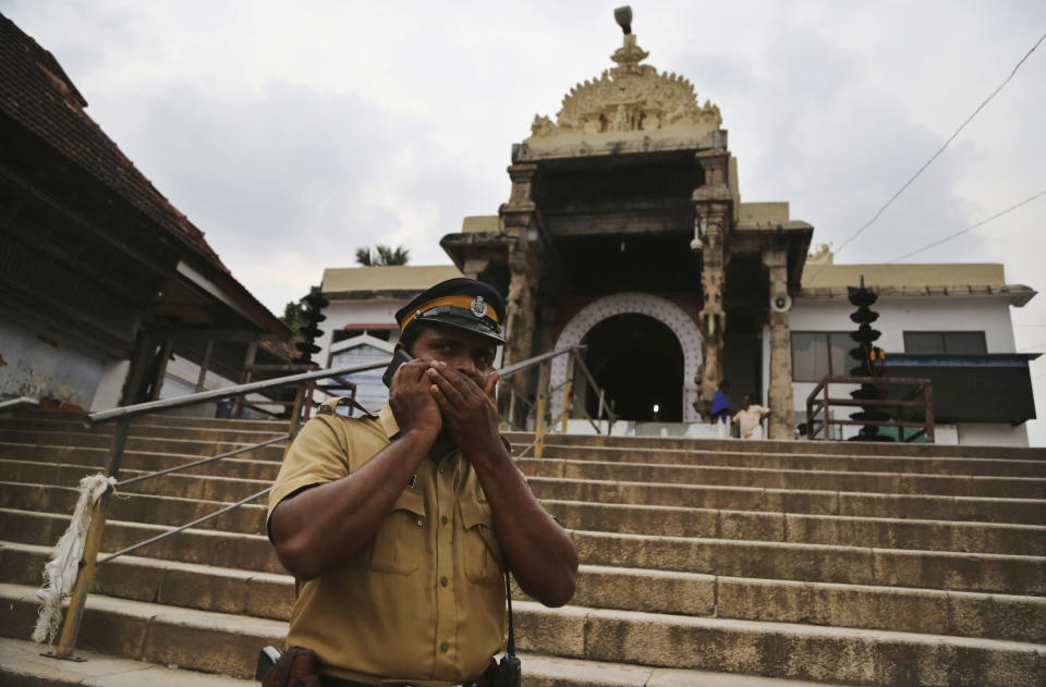 In this Wednesday, Oct. 31, 2018, an Indian police officer talks on his mobile phone as he stands guard outside the 16th-century Sree Padmanabhaswamy temple in Thiruvananthapuram in the southern Indian state of Kerala. (AP Photo/Aijaz Rahi)