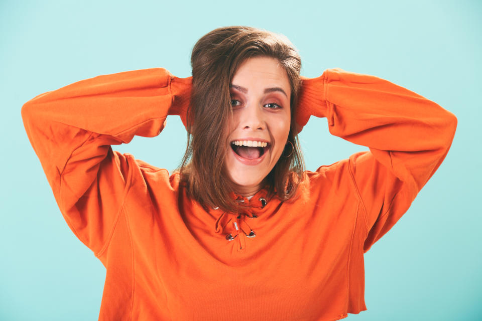 A woman smiling with her hands over her ears