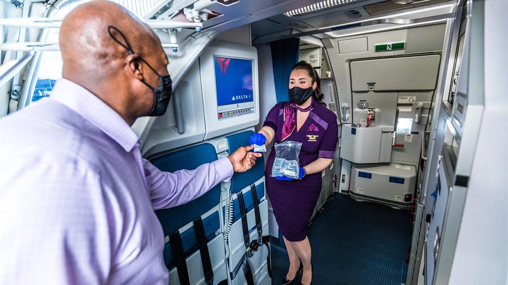 A Delta Air Lines flight attendant welcomes passengers on board.