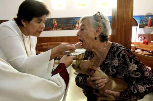 A catholic faithful receives the Eucharist as she brings her pet to be blessed at the Church of Saint Francis of Assisi, patron saint of animals, whose feast marks World Animal Day in Zapopan, Jalisco state in Mexico, on October 4, 2019