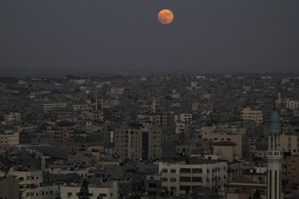 The supermoon rises in the sky over the houses of Gaza City, Wednesday, Aug. 30, 2023. The cosmic curtain rose Wednesday night with the second full moon of the month, the reason it is considered blue. It's dubbed a supermoon because it's closer to Earth than usual, appearing especially big and bright. (AP Photo/Adel Hana)