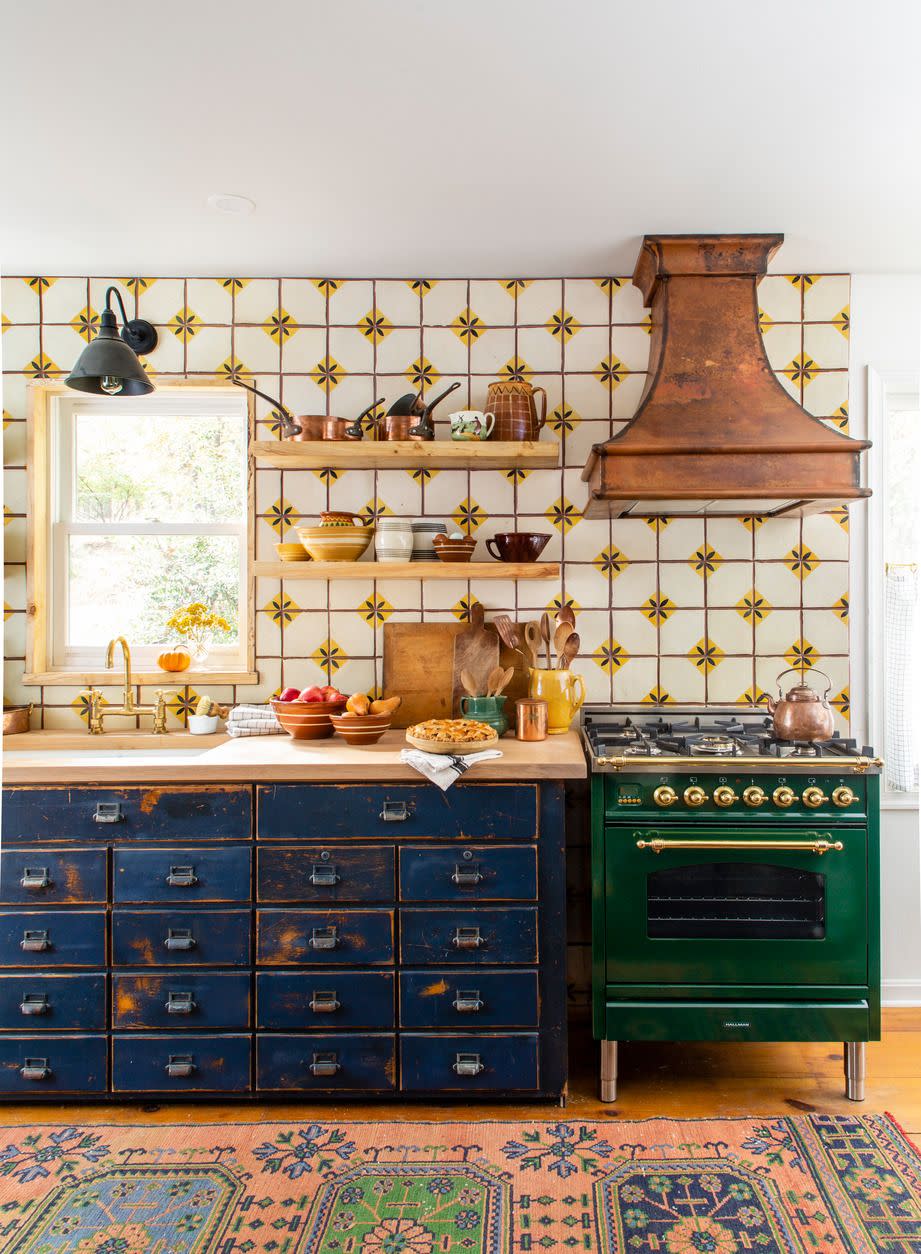 discovered at a barn sale this kitchens blue workbench sets the rustic pieced together feel of this galley kitchen as this is a departure from modern farmhouse style with its deep colors in the stove and cabinets and even the copper hood that lets this small space live large