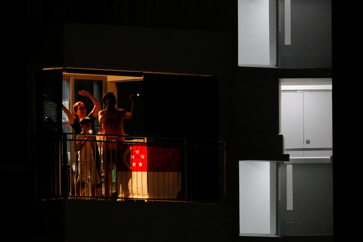 Residents gather at their balconies to sing in tribute to healthcare workers and migrant workers during the COVID-19 outbreak here on 25 April, 2020. (PHOTO: Reuters)