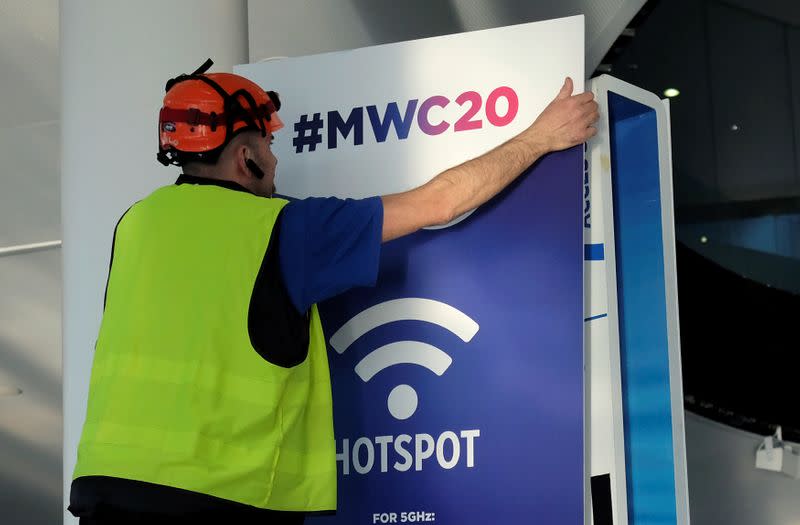 An employee places a banner with information of MWC20 in Barcelona